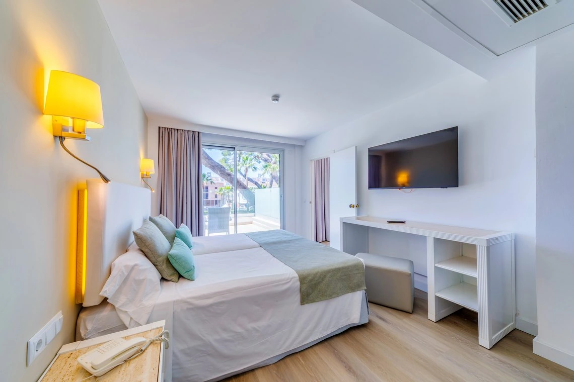 Habitación de hotel moderna con dos camas, Playa Esperanza Resort, balcón y TV.