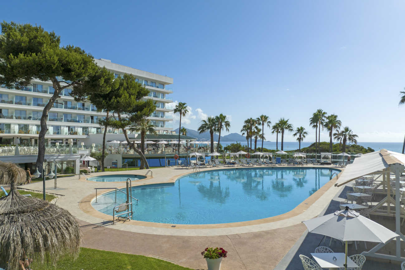Piscina de hotel con palmeras y la Playa Esperanza Resort.