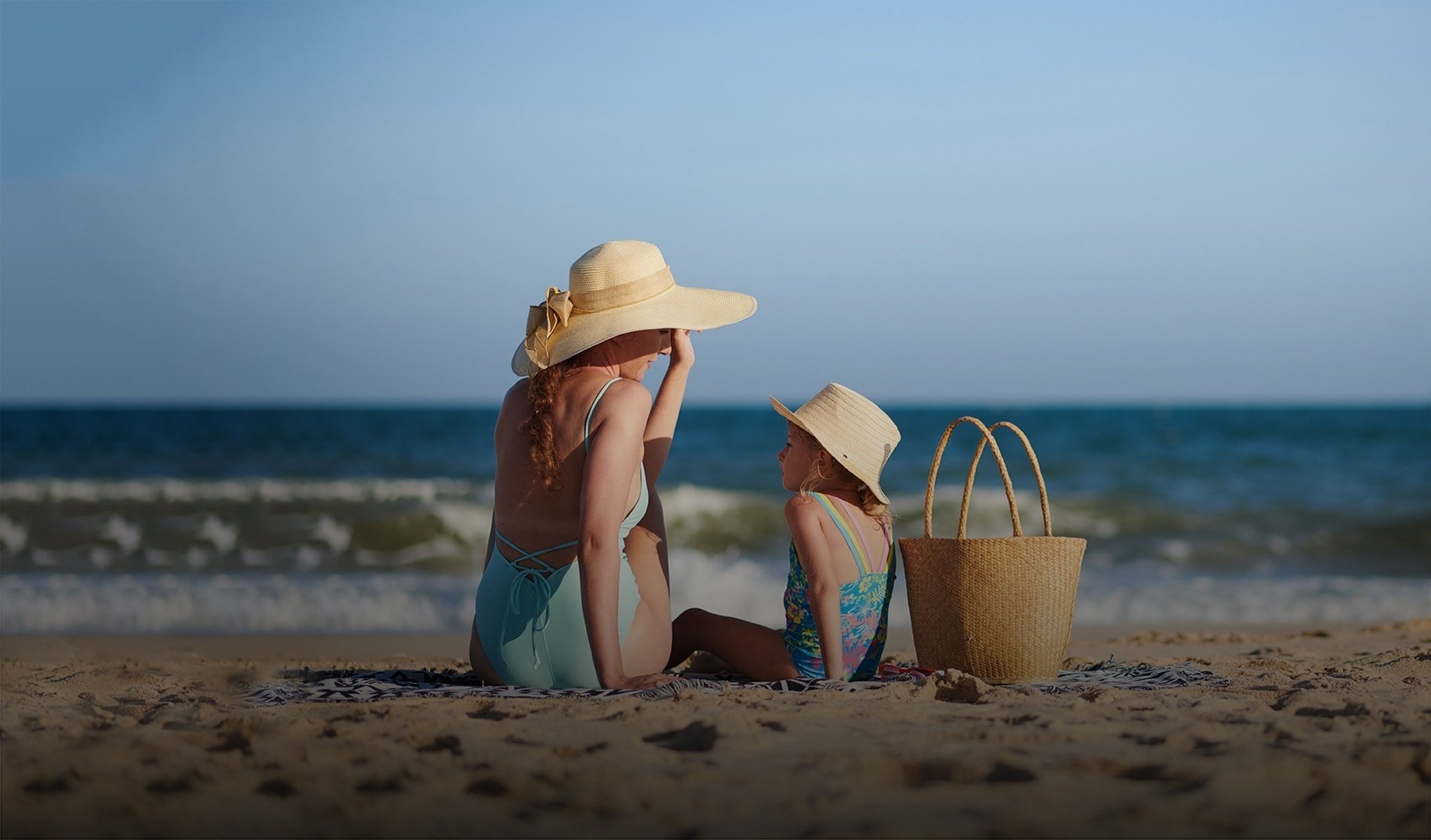 una mujer y una niña están sentadas en la playa