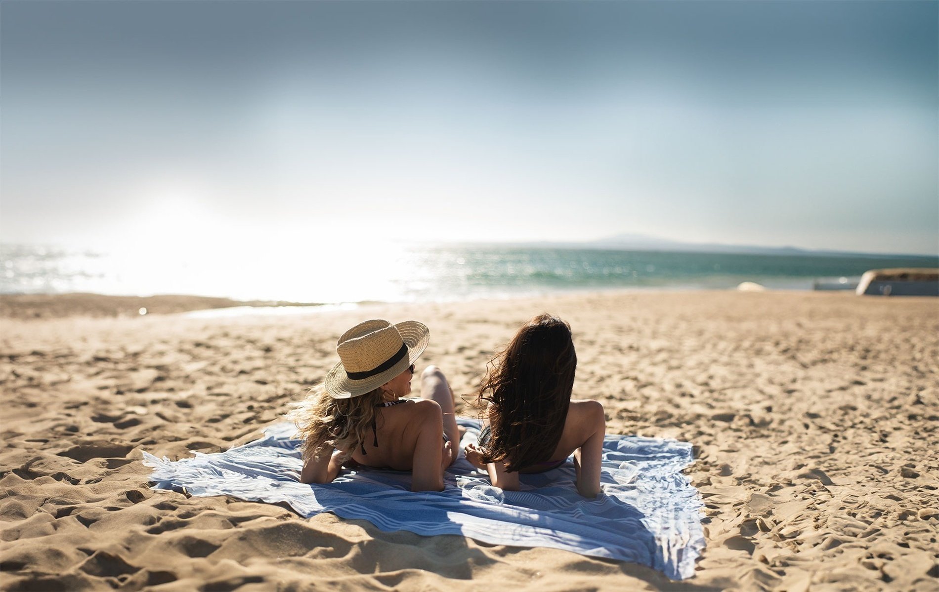 dos mujeres acostadas en la playa miran el océano