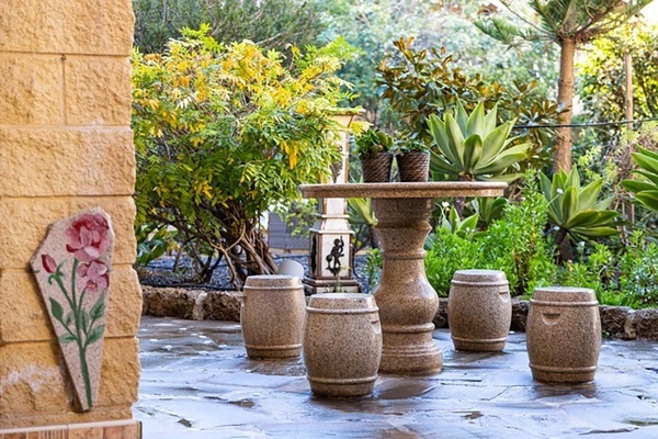 un jardín con una mesa y taburetes de hormigón