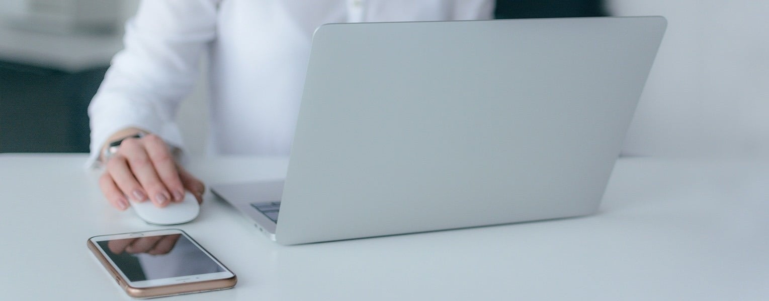 a person using a laptop next to a cell phone