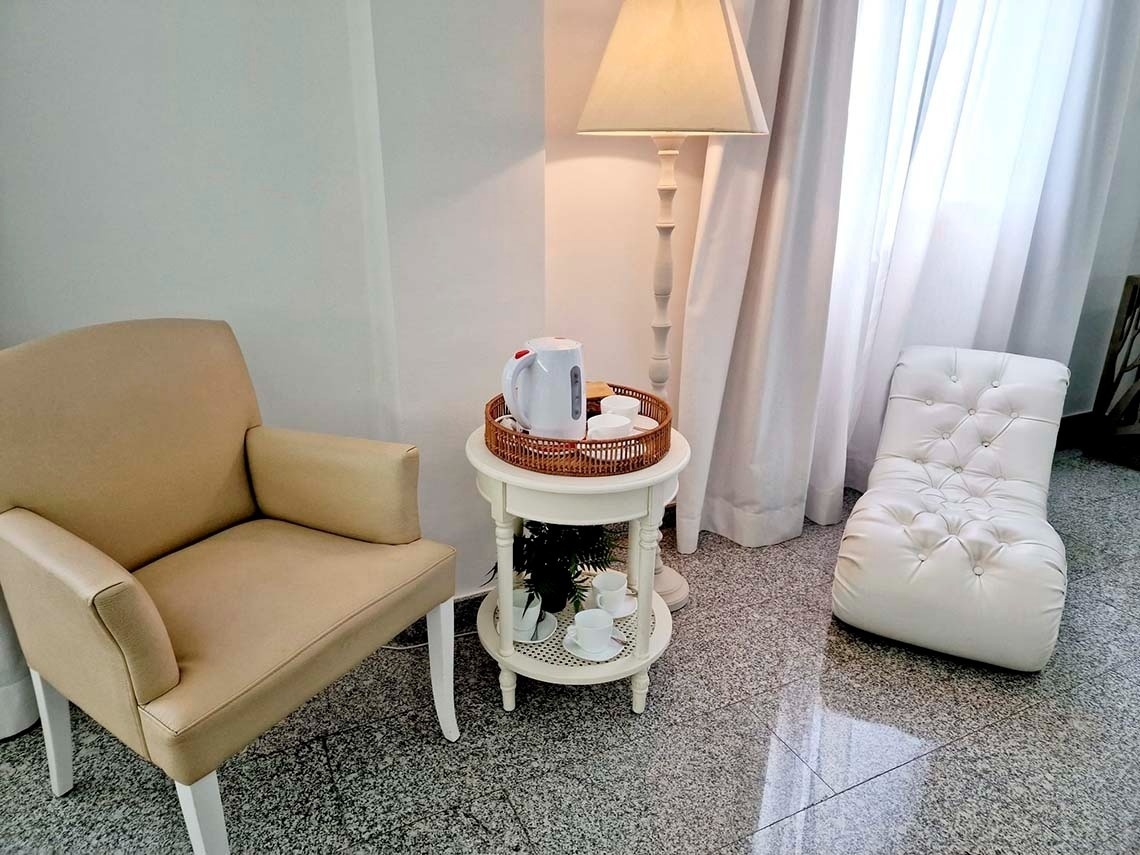 a white chair sits next to a small table with a kettle on it