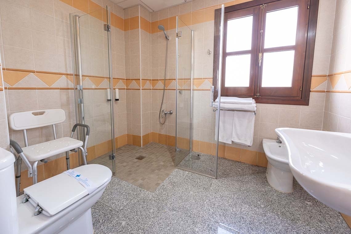 un baño con una silla de ducha y un inodoro