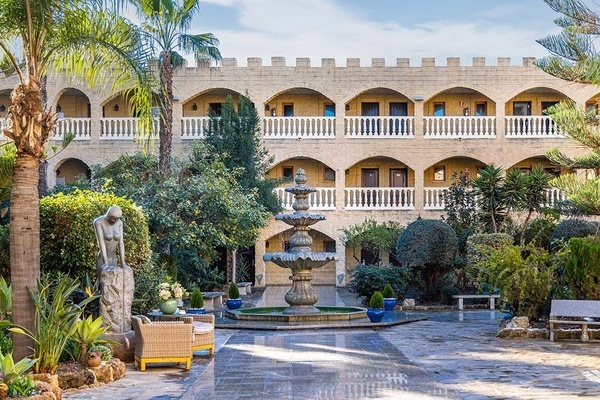 un gran edificio de ladrillo con balcones blancos y una fuente en el medio