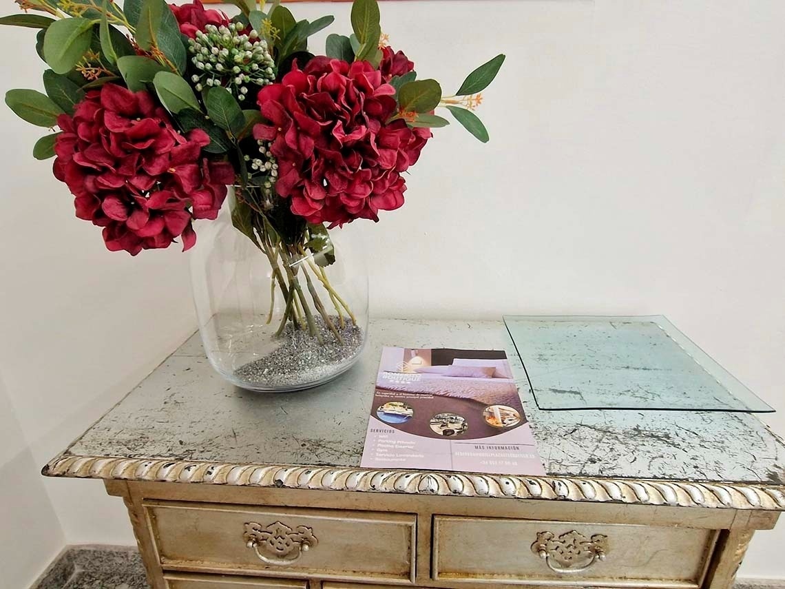 un jarrón de flores rojas se sienta encima de una mesa