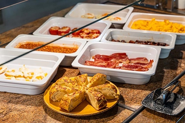 a buffet table with a variety of food including eggs and bacon