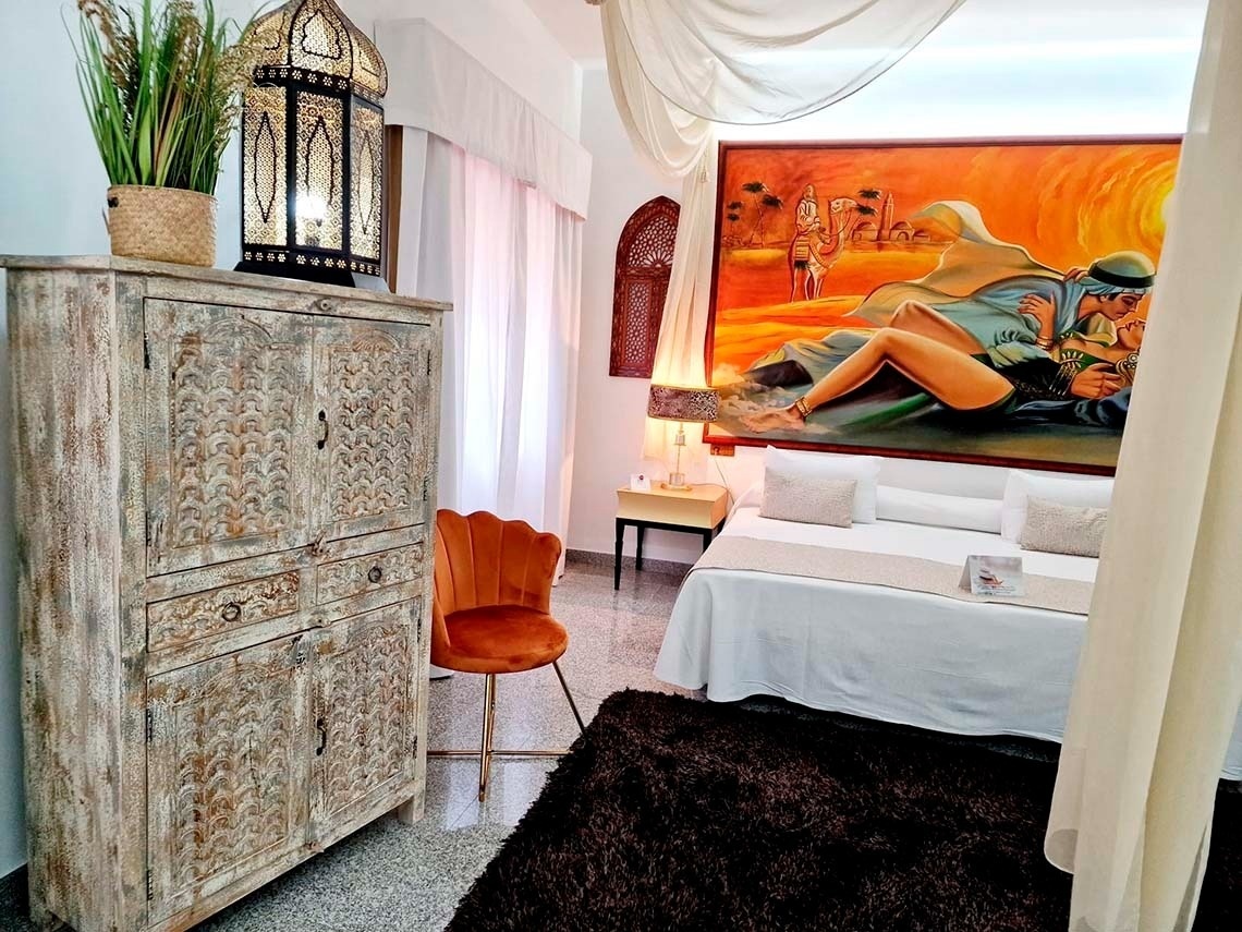 a bedroom with a large painting on the wall above the bed