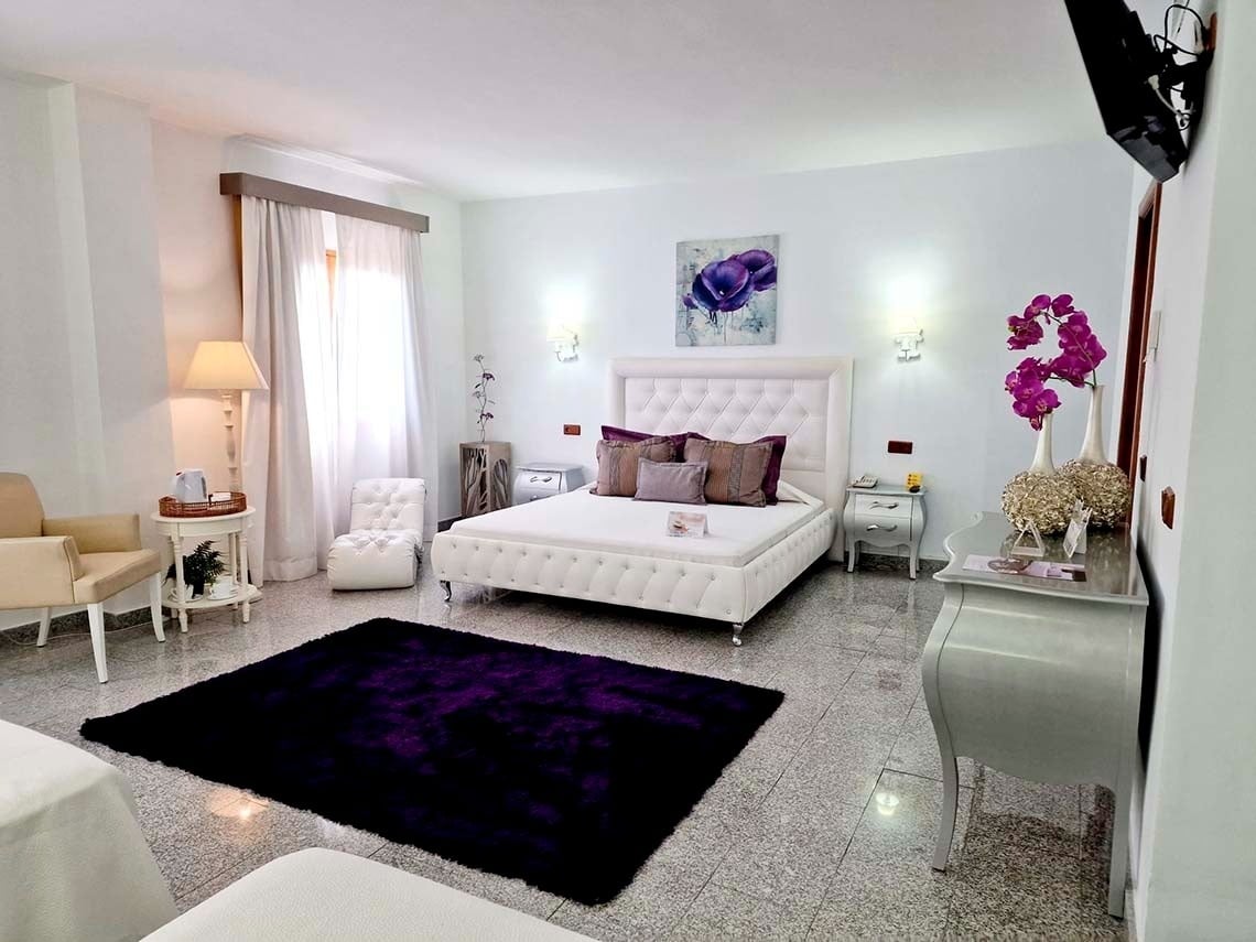 una habitación con una cama blanca y una alfombra morada