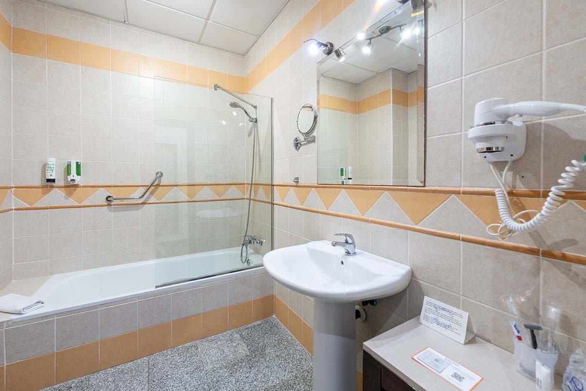 un baño con un lavabo y una bañera y un secador de pelo