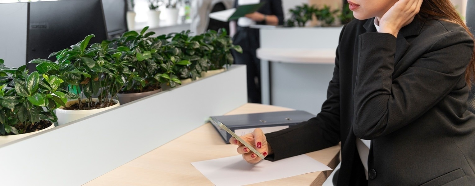 a woman sitting at a desk with a samsung monitor in the background