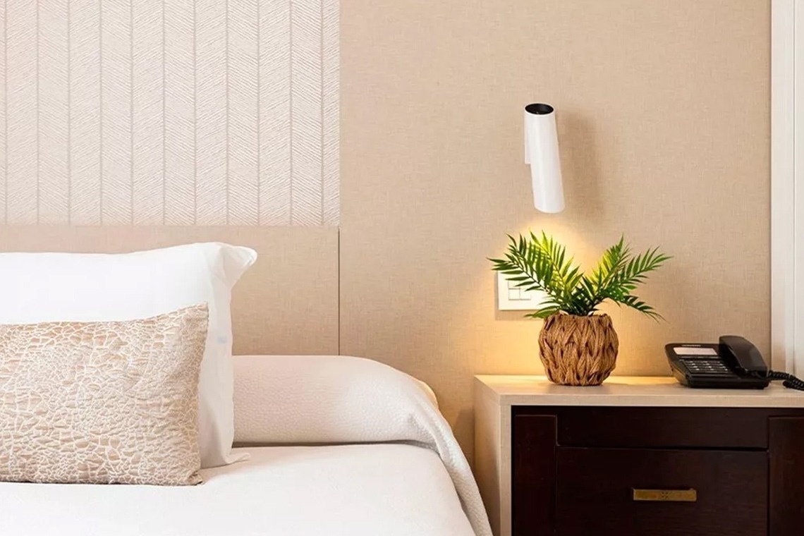 a hotel room with a plant on a nightstand next to a bed