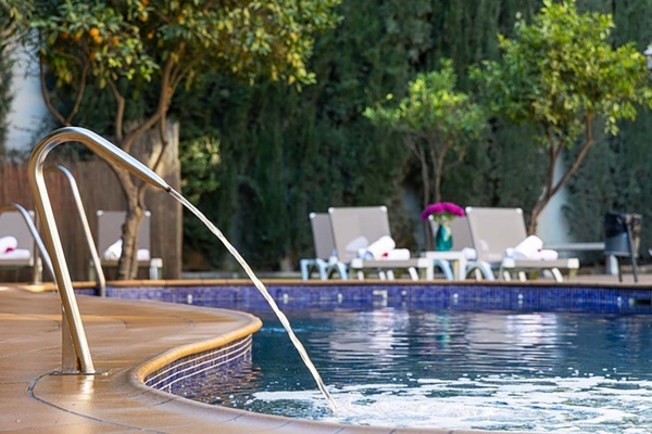 a swimming pool with chairs and trees in the background