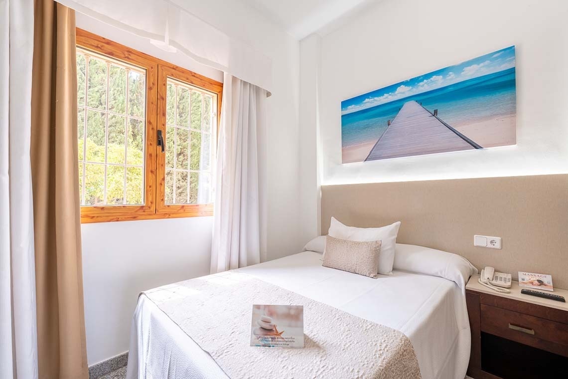 una habitación con una cama y una pintura de un muelle en la pared