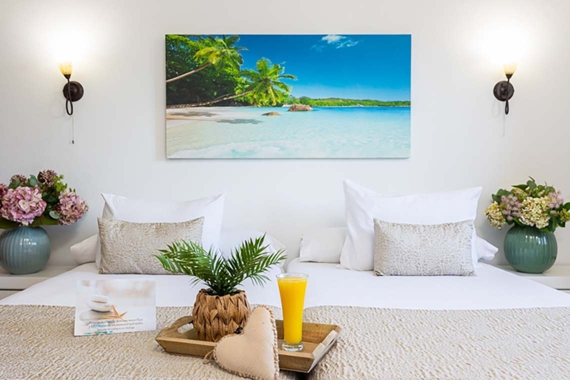 a bed with a picture of a beach on the wall above it