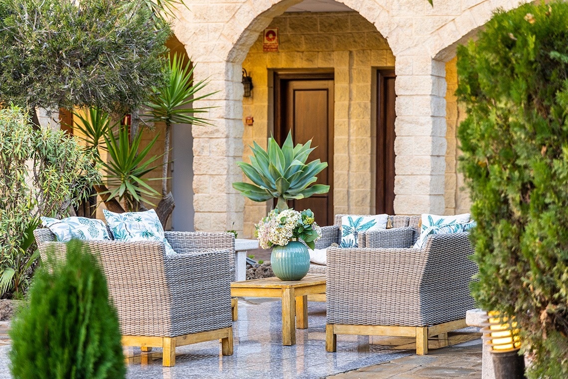 un patio con sillas y una mesa con un jarrón de flores