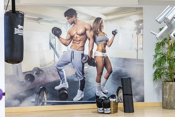 a man and woman lifting dumbbells in a gym with a lonsdale bag