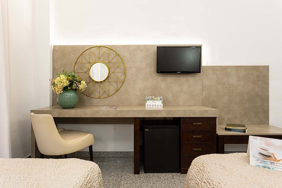 a hotel room with two beds a desk and a flat screen tv