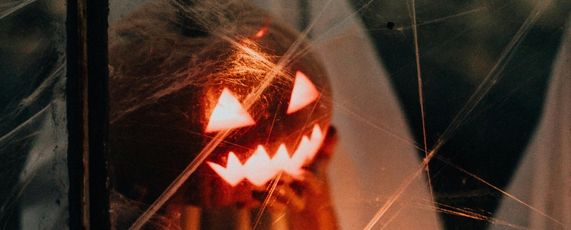 a halloween pumpkin is behind a spider web