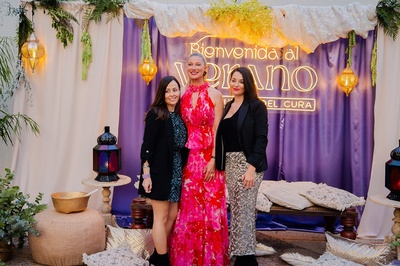 tres mujeres posan para una foto frente a una cortina morada que dice bienvenido al verano - 