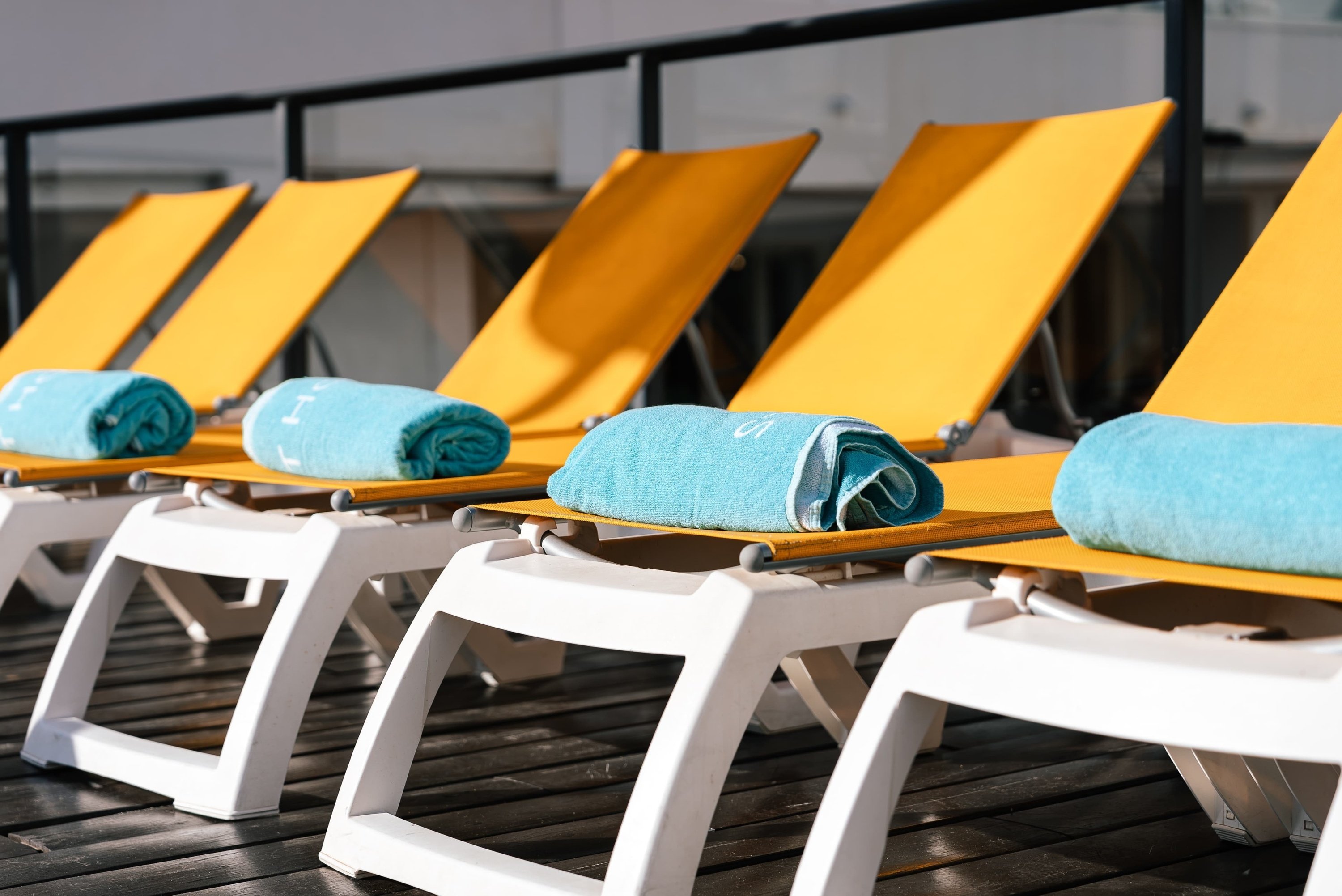 a row of yellow lounge chairs with blue towels on them