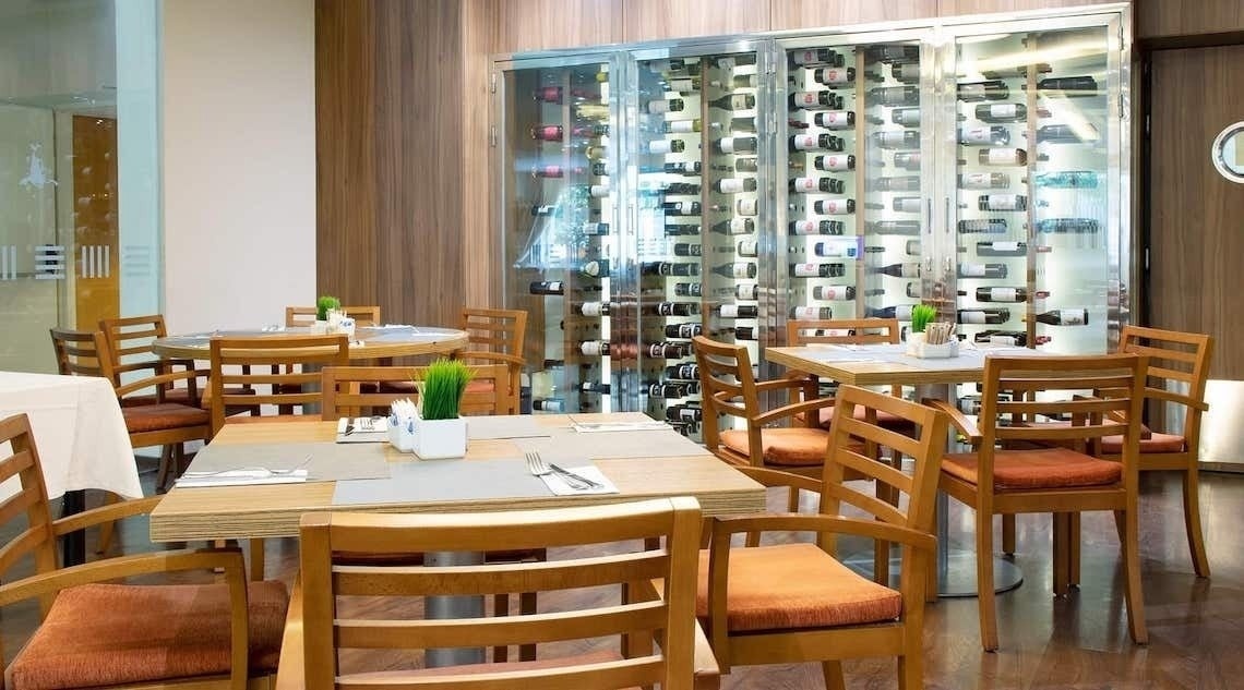 un restaurante con mesas y sillas y una pared de botellas de vino