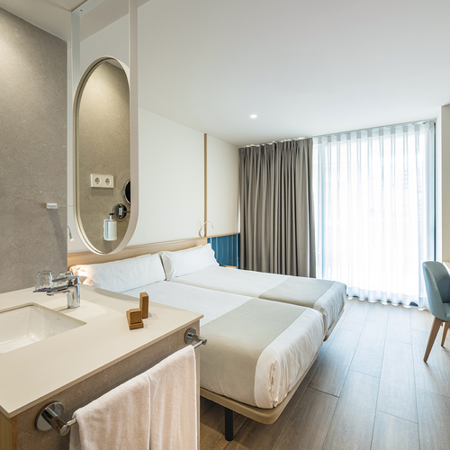 una habitación de hotel con dos camas y un lavabo