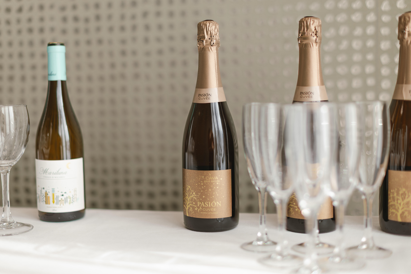 tres botellas de pasión cava están sobre una mesa junto a copas de vino