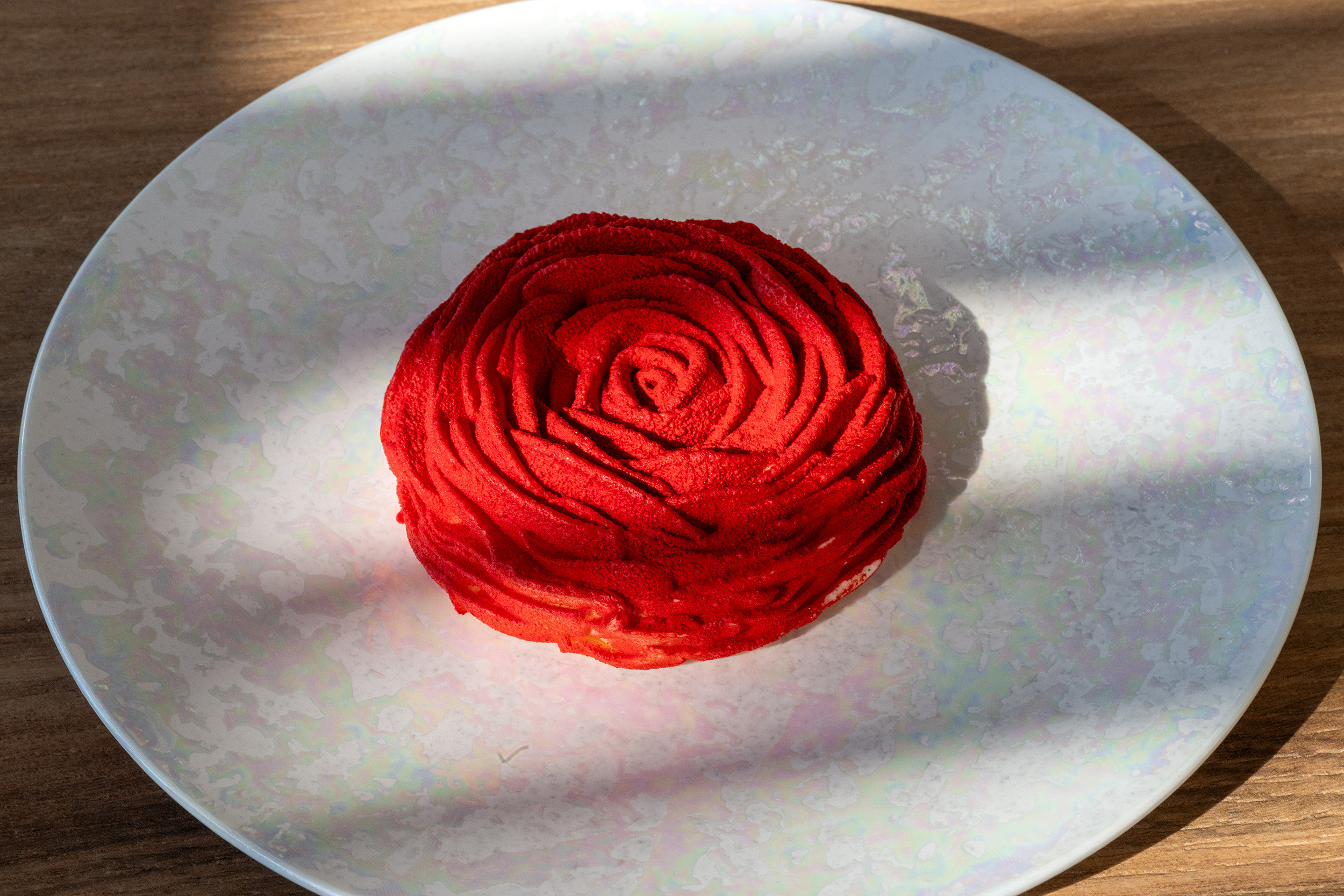 Pastel de postre rosa rojo, Port Hotels: Corporativa sobre plato nacarado, con sombra y luz solar.