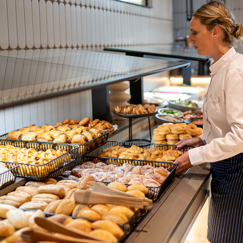 una mujer se sienta frente a un buffet de panadería