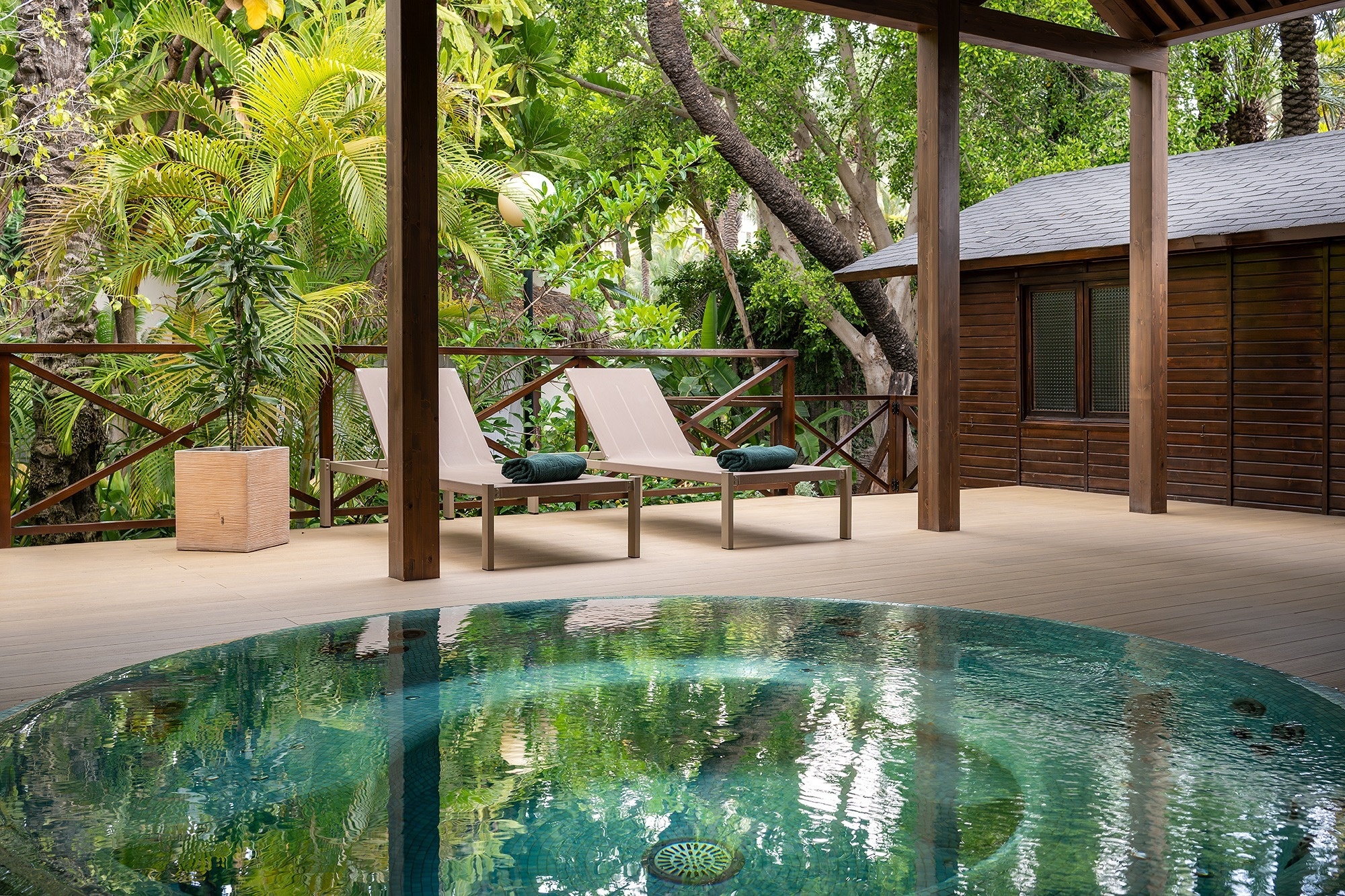 a hot tub is surrounded by lounge chairs under a wooden roof