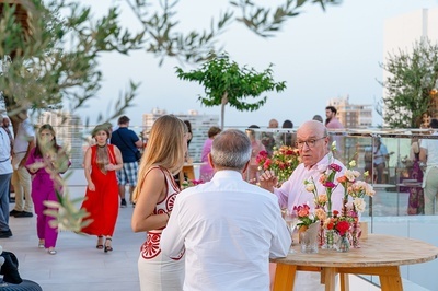 a group of people are standing around a table with flowers on it - 