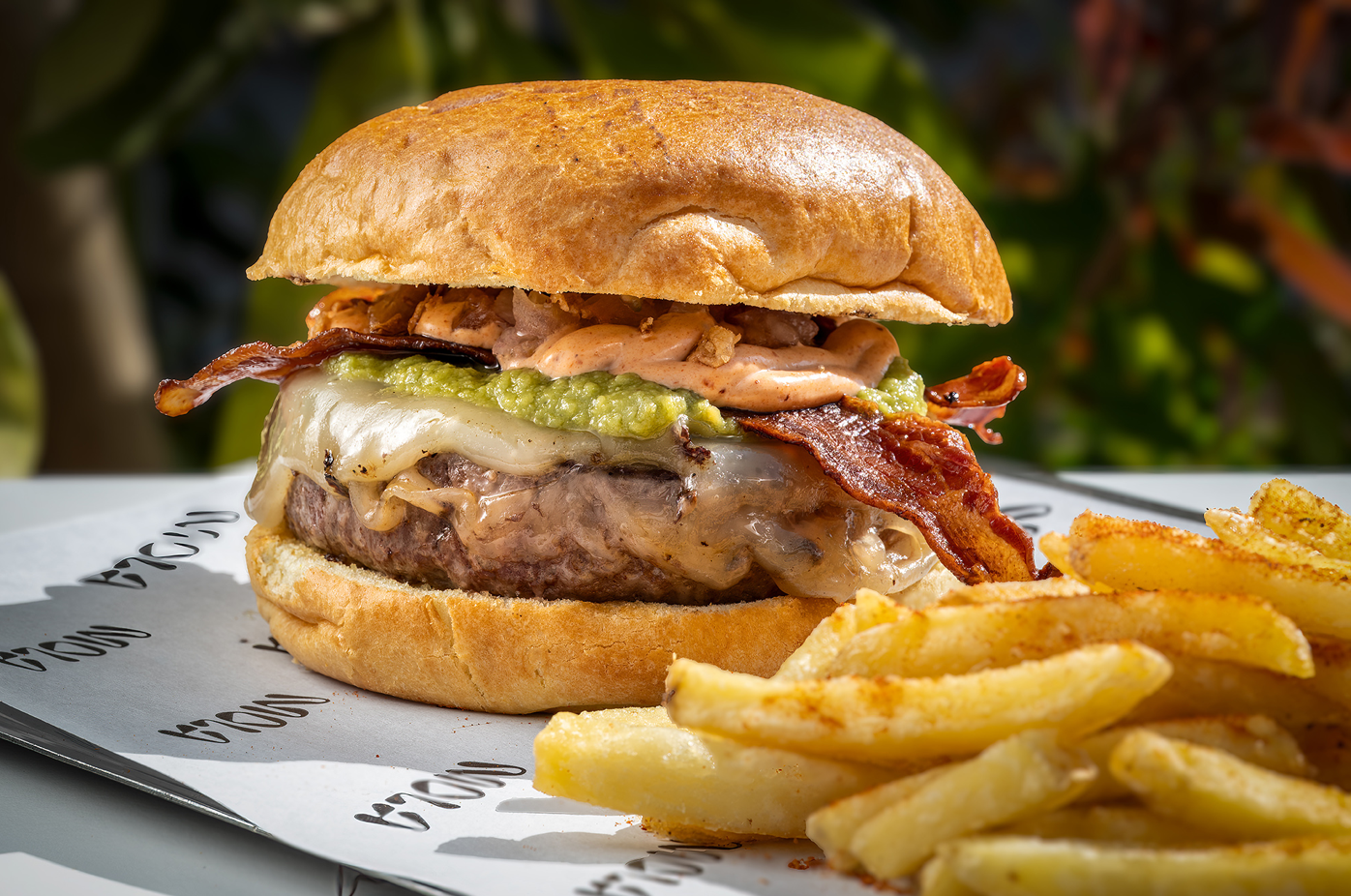 a close up of a hamburger and french fries on a paper that says brown