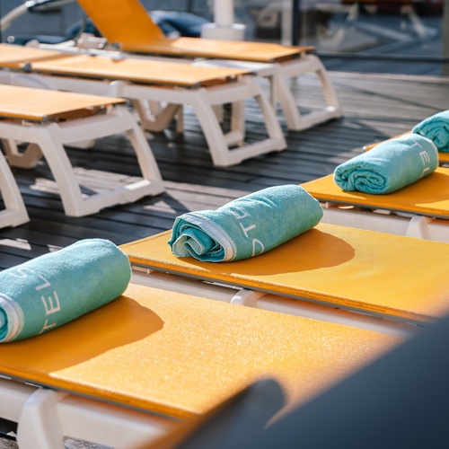 a blue towel with the letter t on it sits on a yellow lounge chair