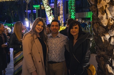 three people posing for a picture in front of a palm tree - 
