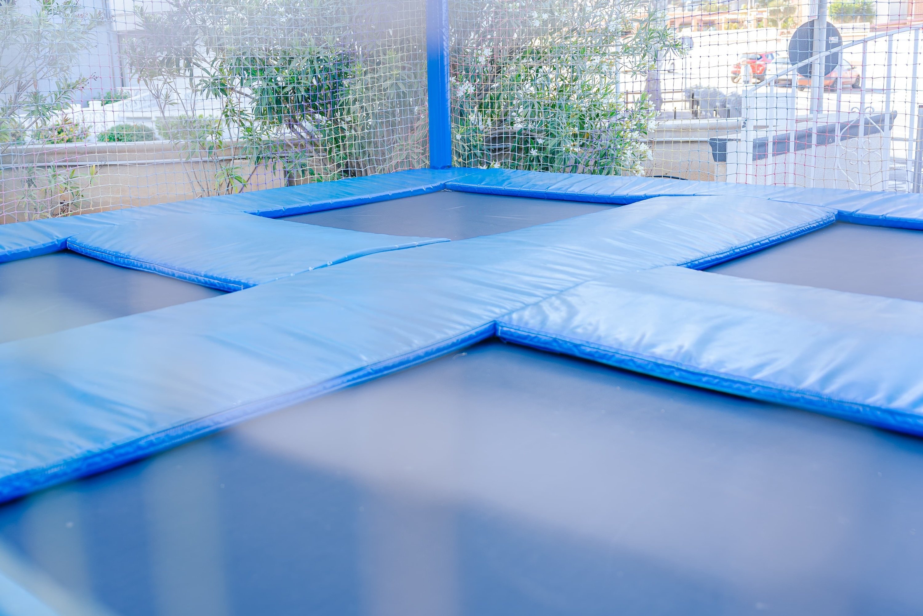 a trampoline with blue cushions and a fence around it