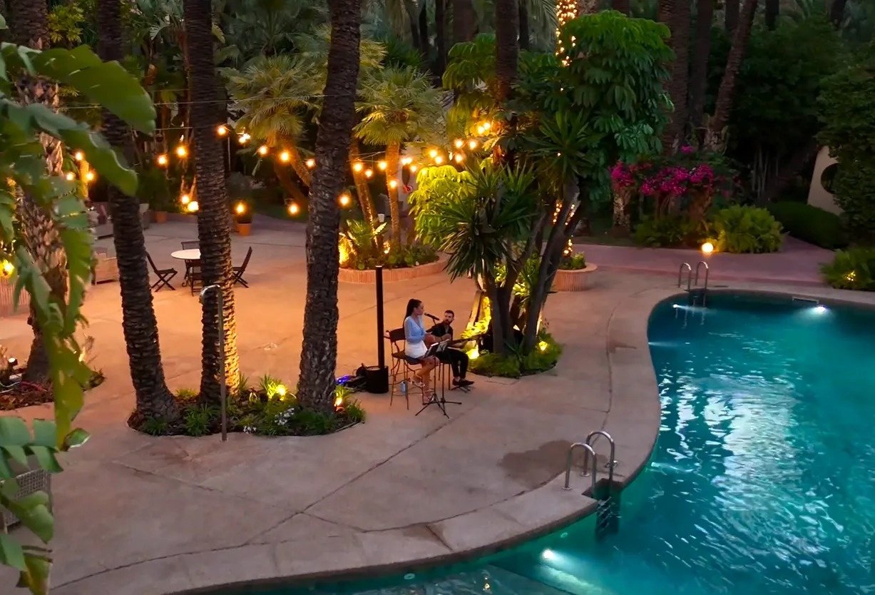 a couple playing instruments next to a swimming pool