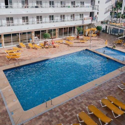 una piscina en un hotel con sillas amarillas alrededor