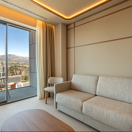 Sofá Port Hotels: Corporativa en sala de estar de hotel con vista a la ciudad y montañas.