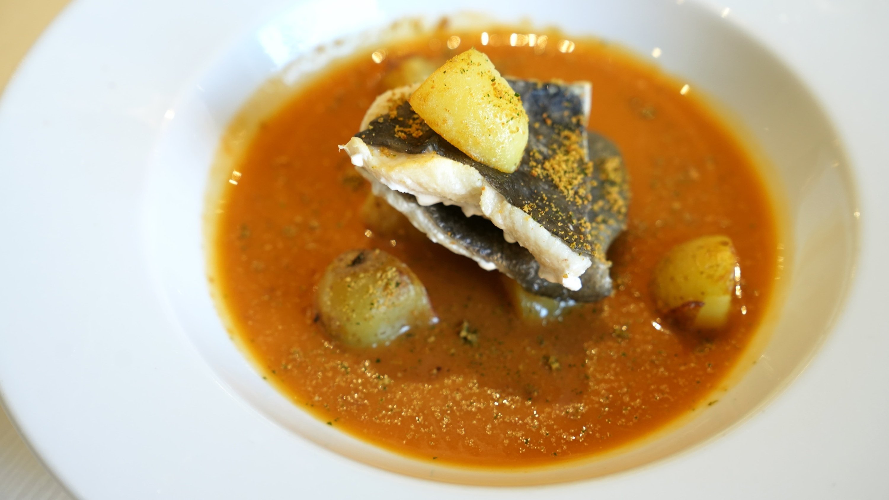 un plato de sopa con un trozo de pescado encima