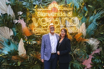 a man and woman standing in front of a sign that says bienvenido al verano - 