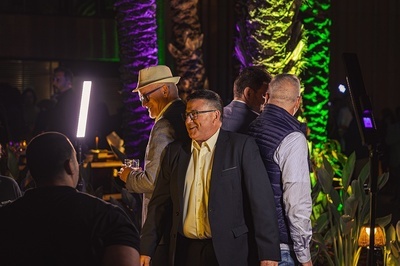 a group of men are standing in a dark room talking - 