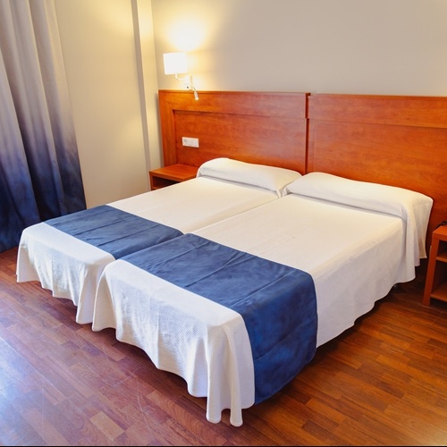Port Hotels: Corporativa - Twin beds with white linens and blue runners in a hotel room.