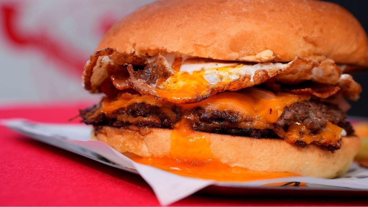 un primer plano de una hamburguesa con queso y huevo frito