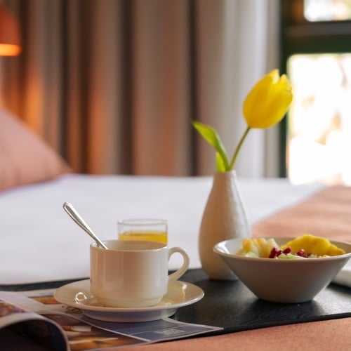 a tray with a cup of coffee and a bowl of fruit sits on a bed