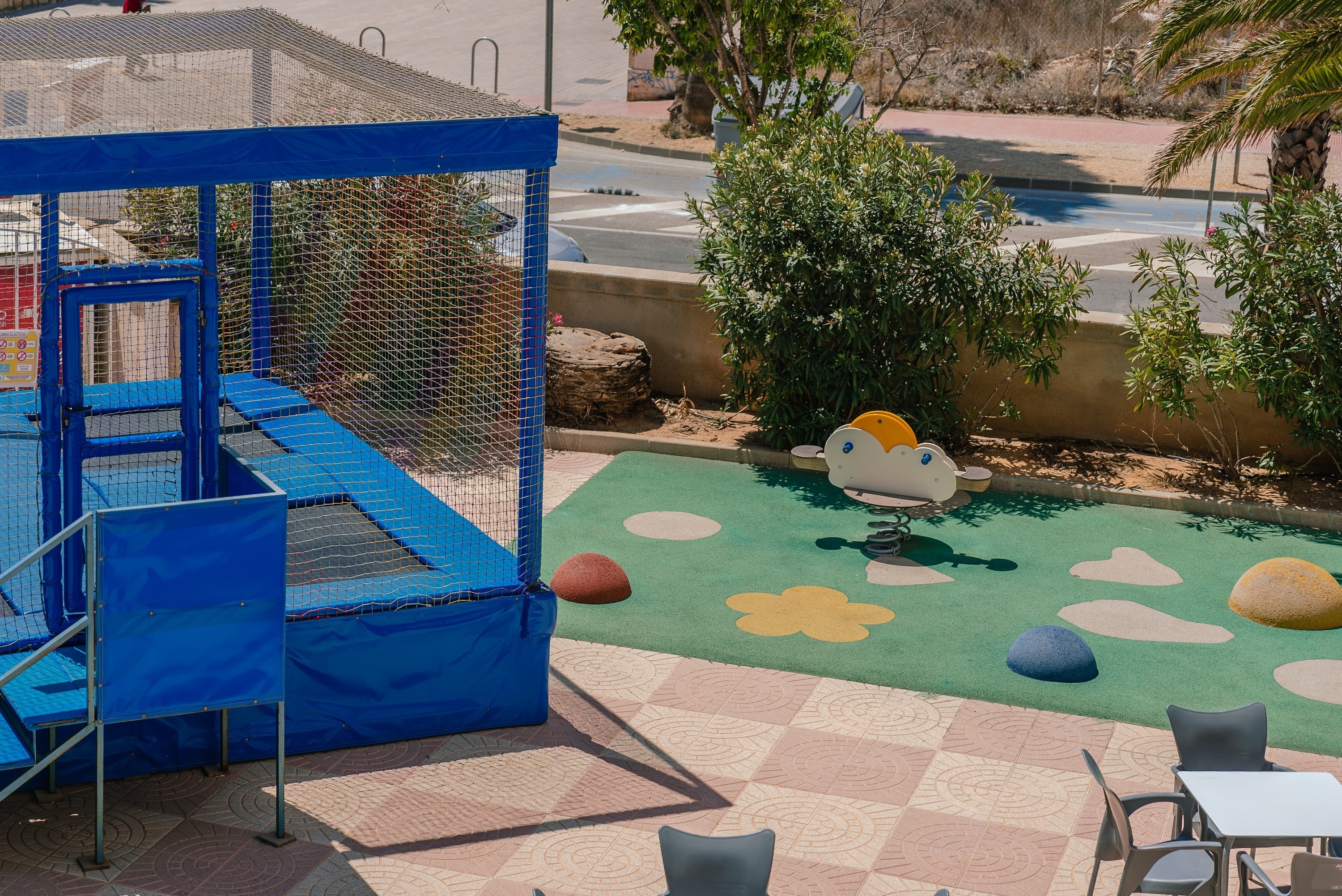 a blue trampoline sits in the middle of a playground