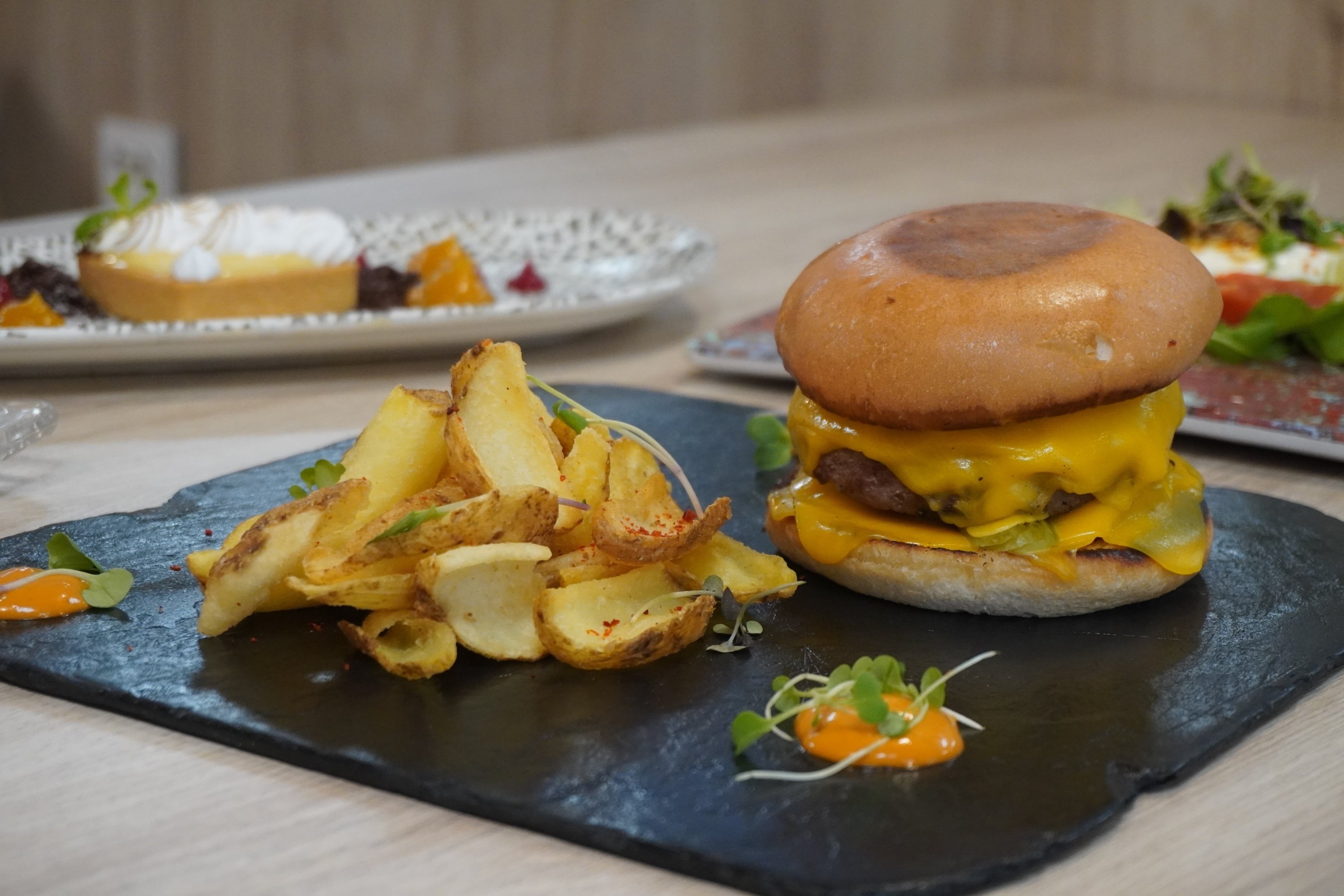 una hamburguesa con queso y papas fritas en una bandeja negra