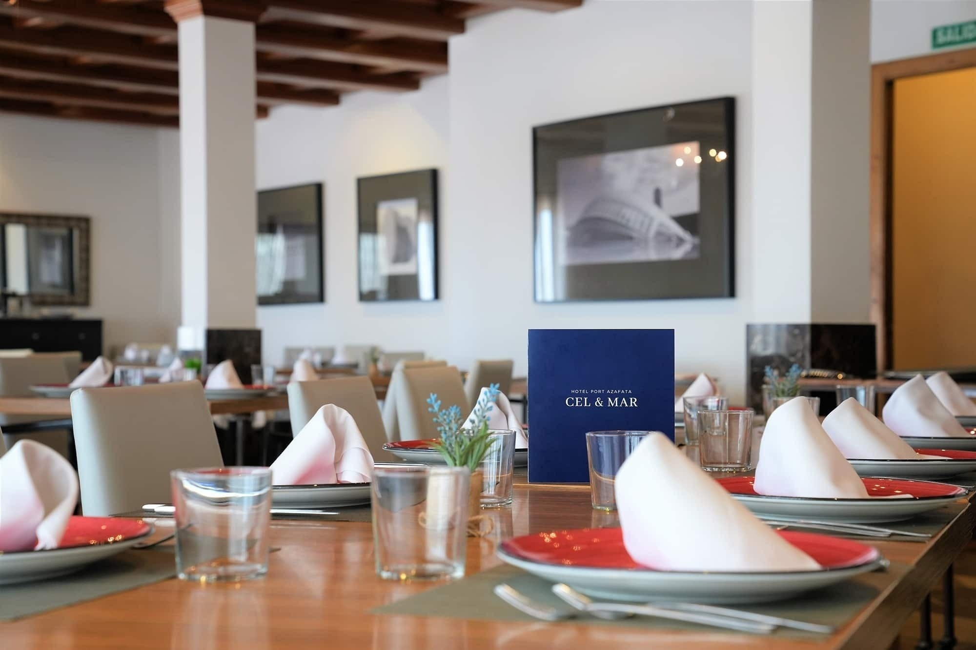 una mesa en un restaurante con platos y vasos y un menú azul que dice cel & mar