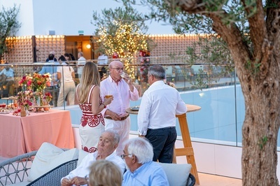 a group of people standing on a balcony drinking wine - 