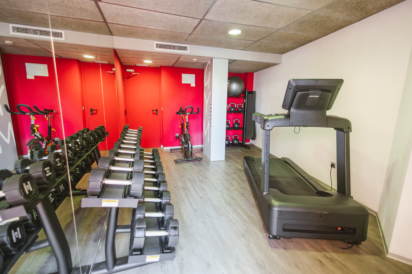 un gimnasio con mancuernas y una cinta de correr